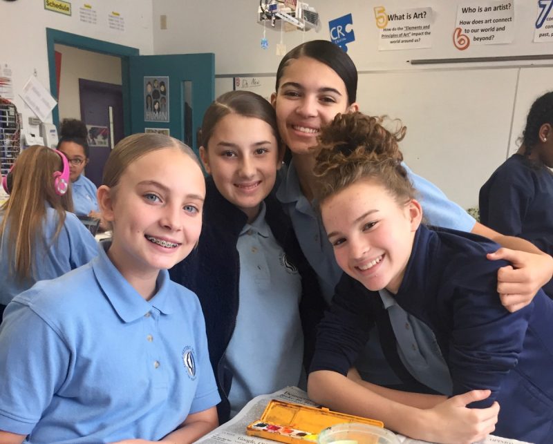 A group of girls looking at the camera in a classroom, smiling.